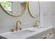 A sleek bathroom with double sinks, gold fixtures, and circular mirrors against white walls at 1423 Ebinport Rd, Rock Hill, SC 29732