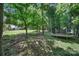 Wooded backyard featuring mature trees, leaves on the ground, and recreational equipment at 1506 Ivy Bluff Way, Matthews, NC 28105