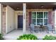 Inviting front porch featuring chairs, stone and vinyl siding, a decorative door, and manicured shrubbery at 159 Saye Pl, Mooresville, NC 28115