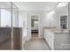 Bright bathroom with double sinks, a walk-in shower, and a view into the spacious main bedroom at 16114 Foreleigh Rd, Huntersville, NC 28078