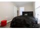 Cozy bedroom featuring a plush, dark-toned comforter, a red stool, and neutral wall color at 2012 Double Oaks Rd, Charlotte, NC 28206