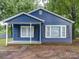 Charming blue home featuring a quaint front porch and freshly painted shutters, nestled among mature trees at 2123 W Sixth Ave, Gastonia, NC 28052