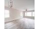 Bright and airy living room with large windows, light gray walls, modern chandelier, and light wood-look flooring at 2123 W Sixth Ave, Gastonia, NC 28052