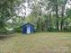 Backyard shed with green grass and surrounded by tall trees. A quaint backyard building at 2123 W Sixth Ave, Gastonia, NC 28052