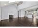 Bright living room with fireplace, dark wood floors, and an open floor plan flowing into the kitchen area at 2830 Berkhamstead Cir, Concord, NC 28027