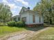 Angle view of the side of the house, showcasing the brick foundation, boarded windows and mature trees at 324 State St, Rock Hill, SC 29730