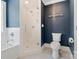 Bathroom with modern white fixtures, glass-enclosed shower, and a toilet against a blue accent wall at 423 State St, Charlotte, NC 28208