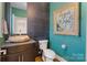 Stylish half bath featuring a unique stone sink, dark tile accent wall, and vibrant turquoise walls at 423 State St, Charlotte, NC 28208