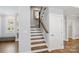 Stairway featuring hardwood treads, white risers, a wood handrail, and a decorative mirror at 423 State St, Charlotte, NC 28208