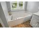 Bathroom featuring a built-in tub with chrome fixtures, surrounded by neutral tiling and natural light at 4860 Sherborne Dr, Harrisburg, NC 28075