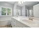 Bright bathroom featuring double sinks with white cabinets, a large mirror, and natural light from a window at 4860 Sherborne Dr, Harrisburg, NC 28075