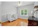 Bright bedroom with hardwood floors, a ceiling fan, a crib, and a window with natural light at 4860 Sherborne Dr, Harrisburg, NC 28075