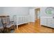 Bedroom featuring hardwood floors, crib, rocking chair, and dresser at 4860 Sherborne Dr, Harrisburg, NC 28075