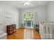 Cozy bedroom featuring hardwood floors, a rocking chair, crib, and a window with natural light at 4860 Sherborne Dr, Harrisburg, NC 28075