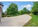 Long concrete driveway leading to a well-maintained home surrounded by lush greenery and mature trees at 4860 Sherborne Dr, Harrisburg, NC 28075
