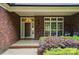 Charming front porch with brick accents, a wooden door, and lush landscaping offering a welcoming entrance at 4860 Sherborne Dr, Harrisburg, NC 28075