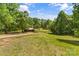 Expansive front yard with mature trees and a glimpse of a barn and fenced pasture in the distance at 536 Brookhaven Rd, Statesville, NC 28625