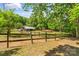 View of a fenced pasture with a barn, surrounded by lush trees offering privacy at 536 Brookhaven Rd, Statesville, NC 28625