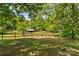 View of a fenced pasture with a barn, surrounded by lush trees offering privacy at 536 Brookhaven Rd, Statesville, NC 28625