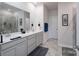 Bright bathroom featuring a double vanity, large mirror, and walk-in shower with grey tiling at 5727 Lavaux Ct, Charlotte, NC 28214
