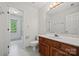 Bathroom with a wood vanity, white tile floor, large mirror, and natural light from the window at 7103 Forest Ridge Rd, Matthews, NC 28104
