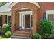 Charming front entrance featuring a classic wood door, brick steps, and manicured landscaping at 7103 Forest Ridge Rd, Matthews, NC 28104