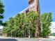 Modern brick condo building surrounded by lush trees and clear blue skies at 715 N Church St # 213, Charlotte, NC 28202