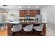 A kitchen island with bar stools, stainless steel appliances, and dark cabinets at 7341 Adare Mews Rd, Charlotte, NC 28217