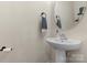 Stylish powder room with a pedestal sink, round mirror and modern fixtures at 7341 Adare Mews Rd, Charlotte, NC 28217
