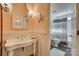 Elegant bathroom with pedestal sink, wainscoting, and tiled shower at 1020 Forbishire Dr, Matthews, NC 28104