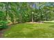 Serene backyard with lush green grass, mature trees, and an outdoor sitting area perfect for relaxation at 104 Whiterock Dr, Mount Holly, NC 28120