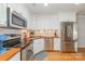 Well-lit kitchen featuring stainless steel appliances, white cabinets, and butcher block countertops at 10617 Fuller Ridge Cir, Charlotte, NC 28270