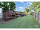 A serene backyard featuring a tiered wooden deck, lush greenery, and manicured lawn for outdoor enjoyment at 113 Marina Ln, Mooresville, NC 28117