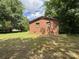 View of the brick home with a backdrop of a large yard and shady mature trees at 13134 Homewood Dr, Charlotte, NC 28262