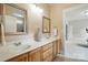 Bathroom featuring double sinks, wood cabinetry, and a large mirror, offering plenty of counter space and storage at 15714 Laurel Oak Cres, Davidson, NC 28036