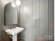 Half bath featuring a pedestal sink, decorative mirror, and paneled walls that add architectural detail and character at 15714 Laurel Oak Cres, Davidson, NC 28036