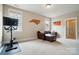 Bright bonus room with plush carpet, brown leather couch, stationary bike, and patriotic decorations at 15714 Laurel Oak Cres, Davidson, NC 28036