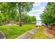 Lush green backyard overlooking the lake with chairs by a fire pit at 18028 Broken Woods Rd, Charlotte, NC 28278