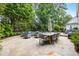 Expansive stone patio with an outdoor dining area and fire pit, surrounded by lush landscaping and mature trees at 18705 Harbor Light Blvd, Cornelius, NC 28031