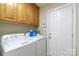 Functional laundry room featuring modern washer, dryer, oak cabinetry, and door to the exterior at 2020 Olde Towne Dr, Monroe, NC 28110