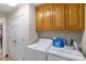 Functional laundry room featuring modern washer, dryer, oak cabinetry, and interior doors at 2020 Olde Towne Dr, Monroe, NC 28110