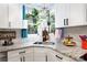 The kitchen sink is surrounded by white cabinets and features greenery with a blue curtain at 27037 Tidal Way, Tega Cay, SC 29708