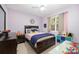 Bedroom with a dark-wood bedframe, side table, and large window with light-purple walls at 2804 Pulaski Dr, Monroe, NC 28110