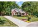 Charming brick home with lush landscaping, manicured lawn, and a long driveway, enveloped by mature trees at 2804 Pulaski Dr, Monroe, NC 28110