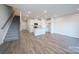 Open-concept living room and kitchen featuring wood-look floors, white cabinets, stainless appliances, and a staircase at 4213 Summit Woods Dr, Charlotte, NC 28216