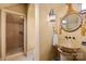 This bathroom features a stand up shower with glass door, unique stone sink, and decorative mirror and sconces at 4523 Fox Brook Ln, Charlotte, NC 28211