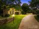 Exterior shot of a home with lush landscaping, outdoor lighting and a circular driveway at 4523 Fox Brook Ln, Charlotte, NC 28211