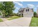 Two-story home featuring a large driveway, well-maintained lawn, garage and mature trees at 4711 Sunburst Ln, Charlotte, NC 28213