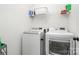 Modern laundry room featuring a white washer and dryer with wire shelf above at 4711 Sunburst Ln, Charlotte, NC 28213