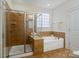 Bright bathroom featuring a glass shower, soaking tub with tile surround, and a large window at 5663 Morris Hunt Dr, Fort Mill, SC 29708